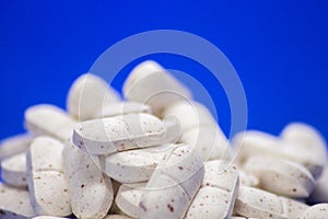 Many white medicine tablets on blue background. White pills, concept Ã¢â¬â pharmacy. Medicines drugs.